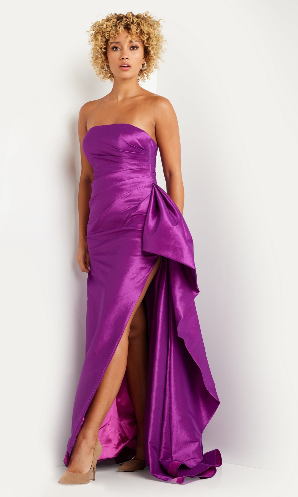 A woman stands against a white background wearing the Long Prom Dress 36854 by Jovani—a bright purple, strapless taffeta gown with a fitted long silhouette, side slit, and draped detail.